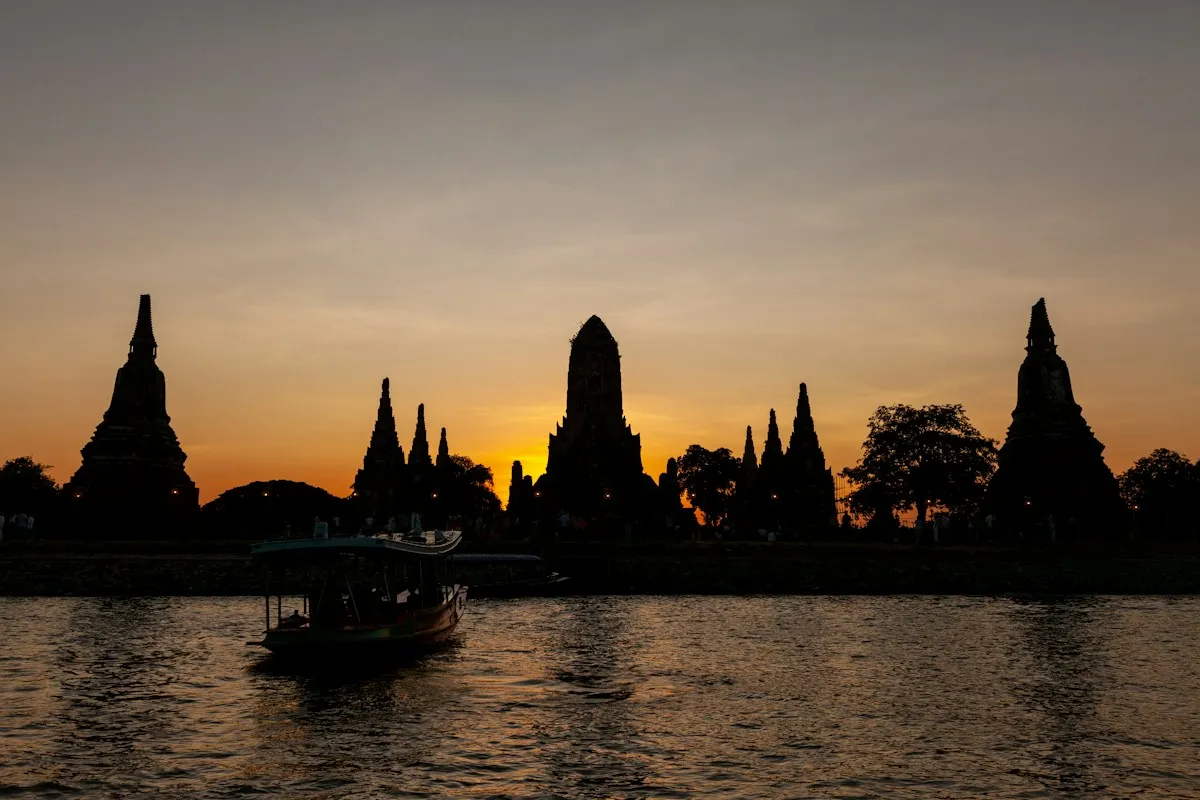 เงาวัดไชยวัฒนารามริมแม่น้ำยามพระอาทิตย์ตก มีเรือล่องผ่าน